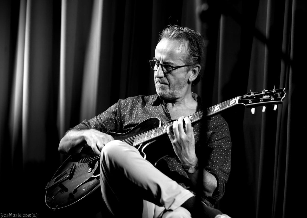 Dave Kelbie on stage playing guitar