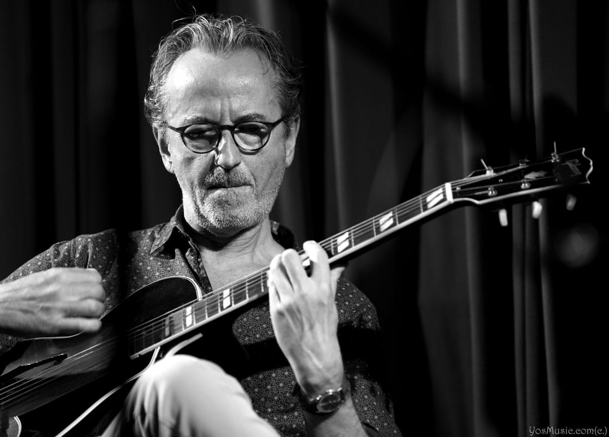 Dave Kelbie on stage playing guitar