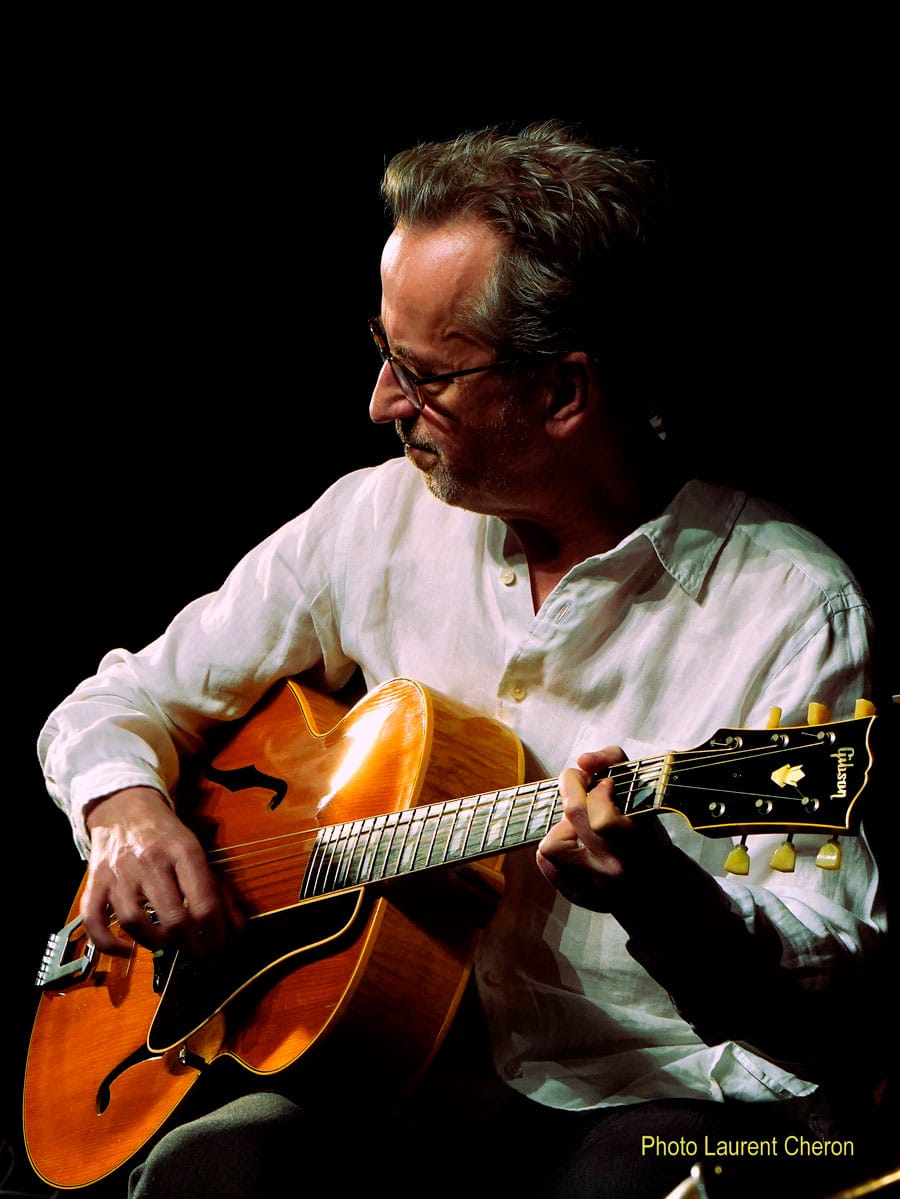 Dave Kelbie on stage playing guitar