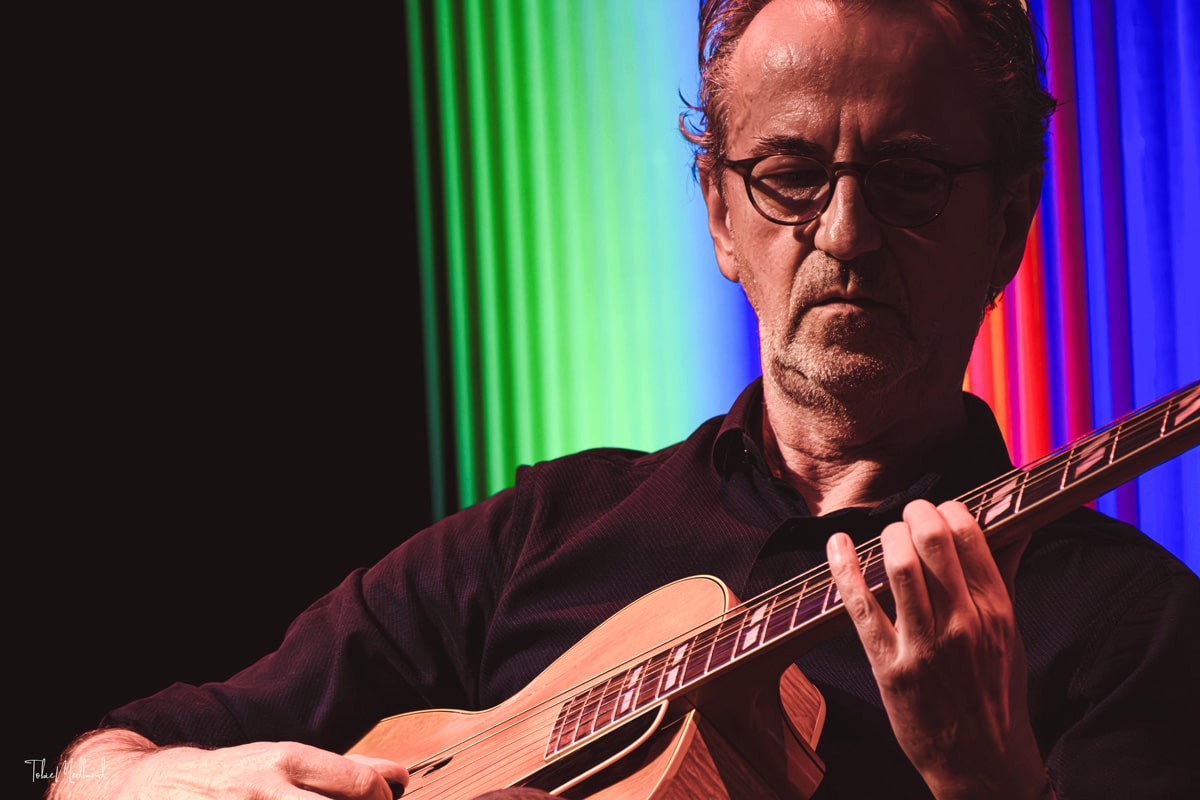Dave Kelbie on stage playing guitar